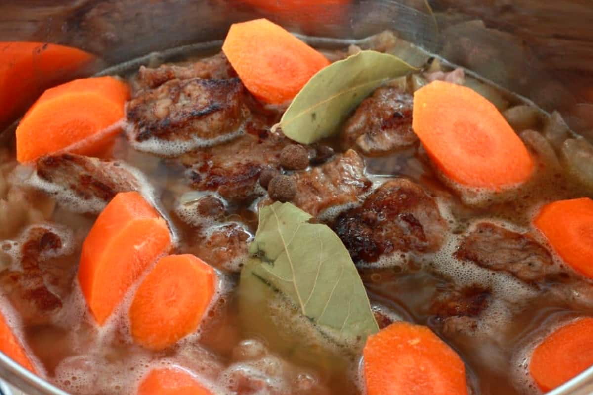 adding broth, veggies and spices and cooking in pot