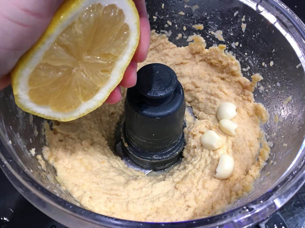 adding lemon juice and garlic to chickpeas
