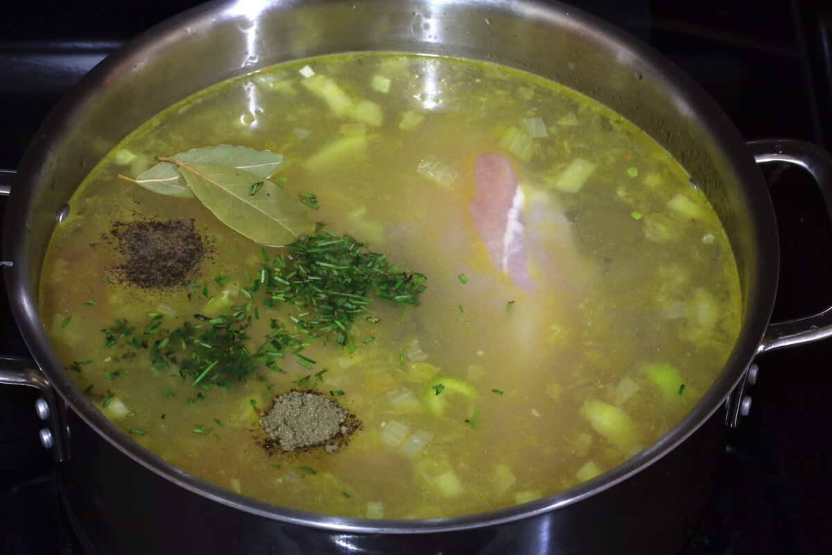adding broth and herbs to soup