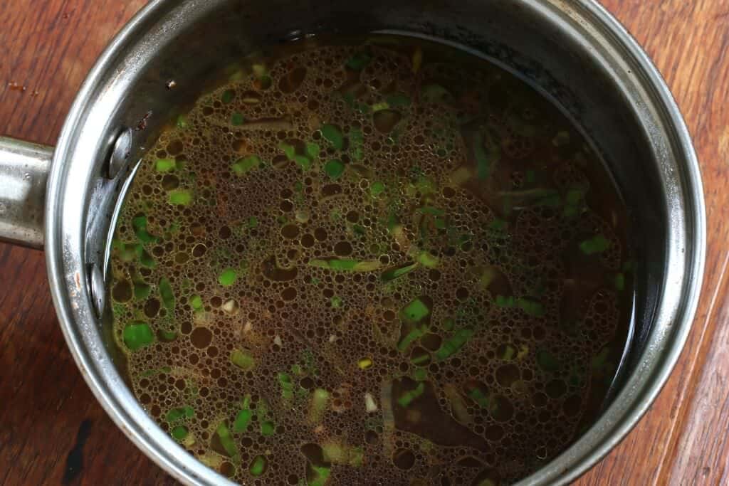 adding broth to saucepan