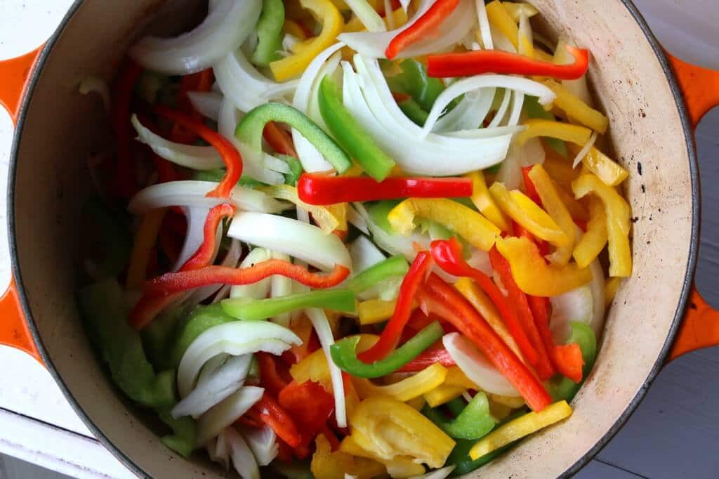 adding onions and peppers to Dutch oven