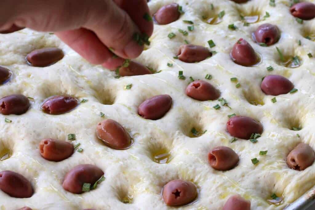 sprinkling rosemary onto dough