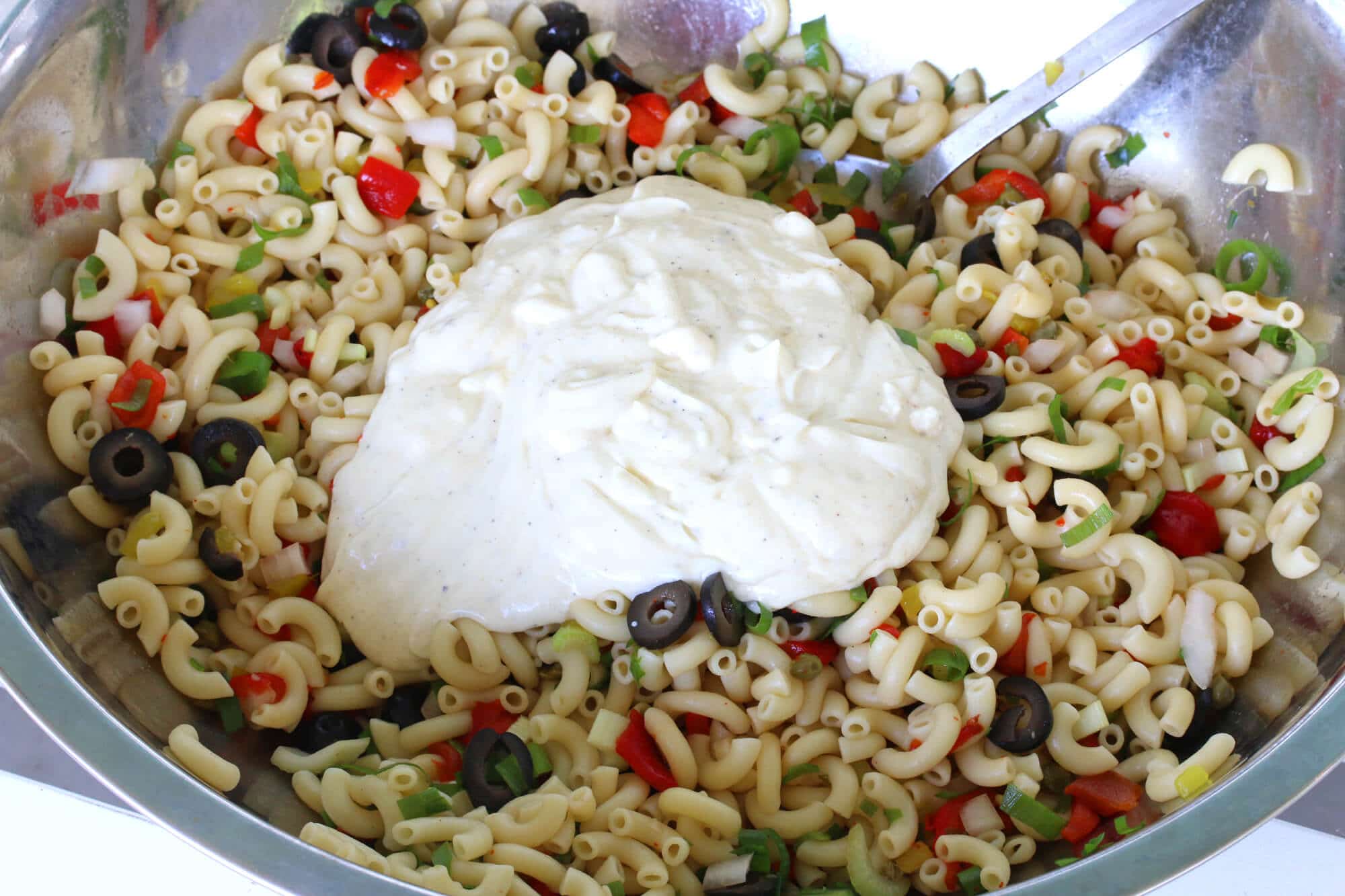 adding the dressing to the pasta