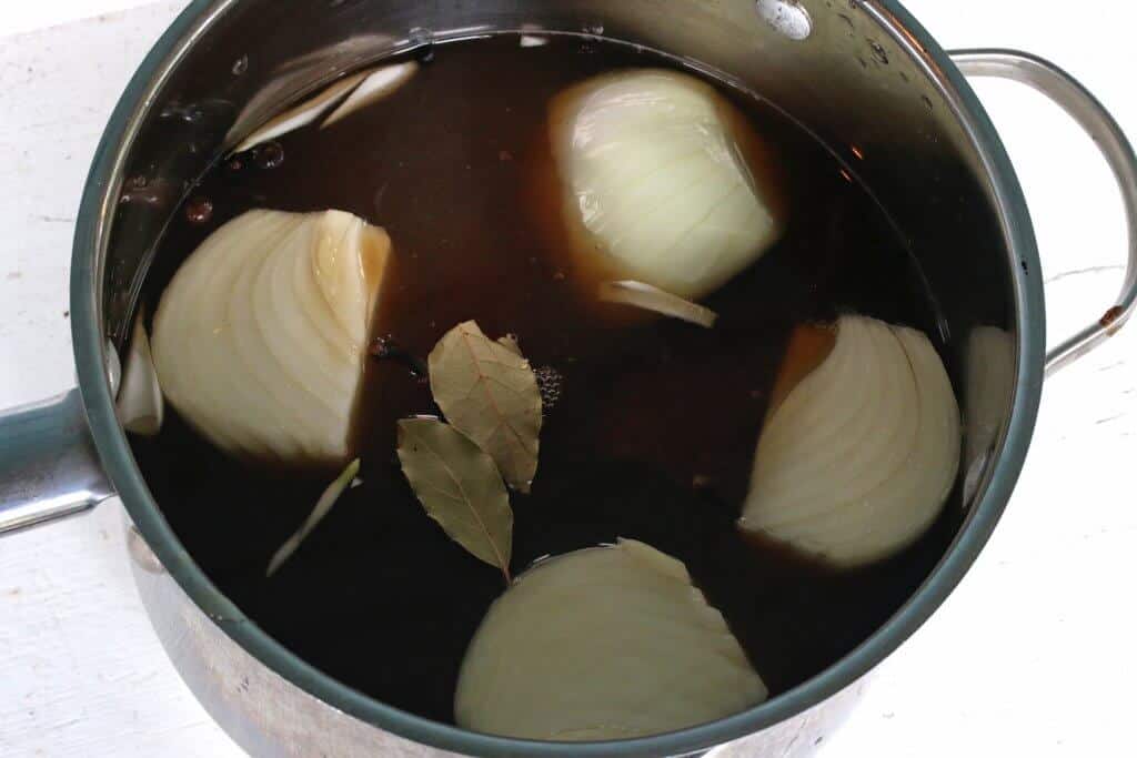 adding the liquids onions and bay leaves to a pot