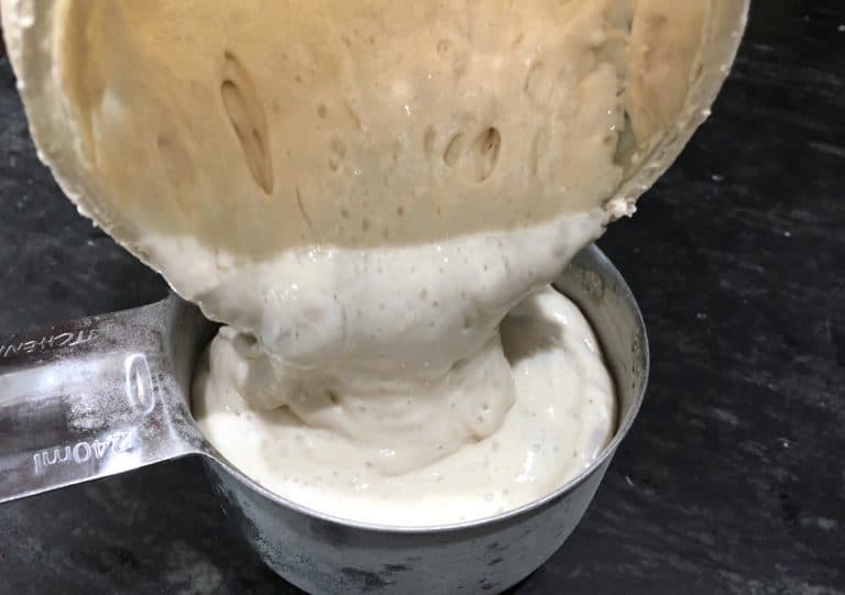 pouring sourdough into measuring cup