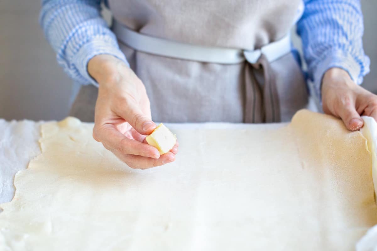 rolling out dough and buttering the surface