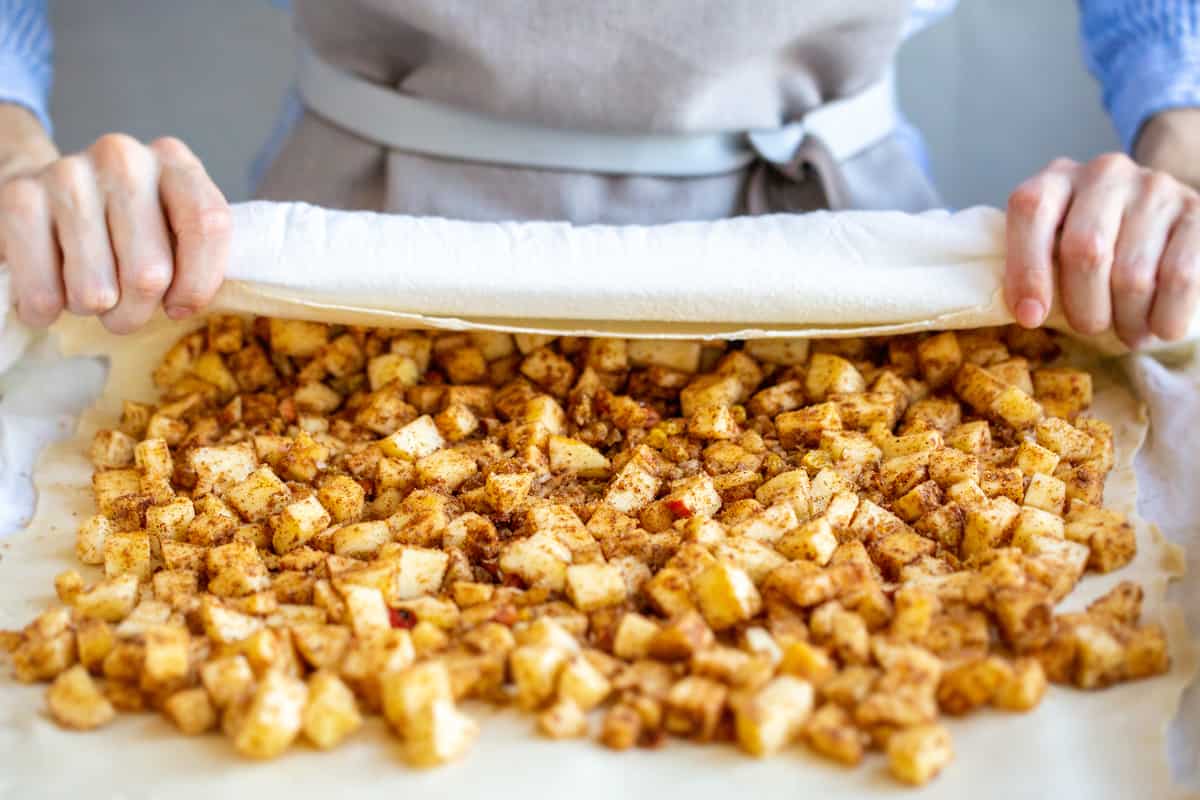 placing apples on dough and rolling it up